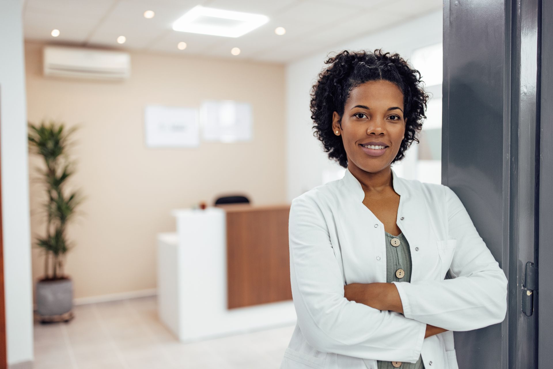 Confident professional standing with arms crossed in an office setting.
